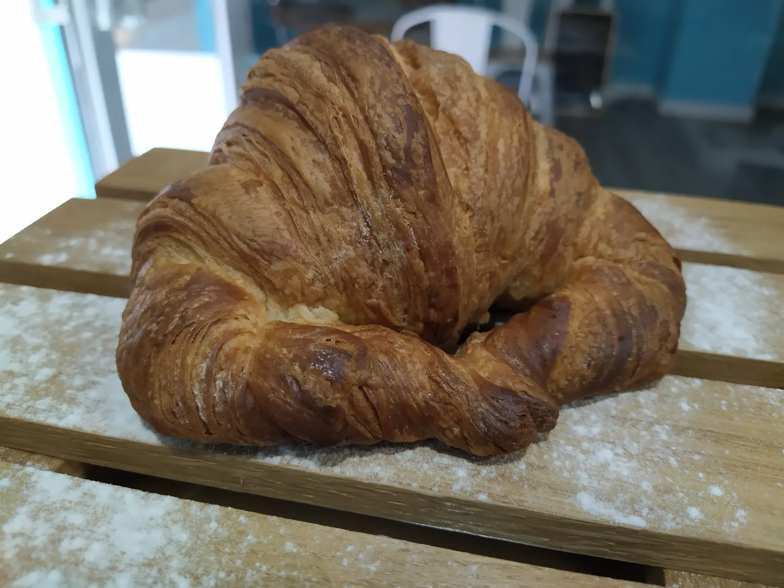 Croissant de mantequilla recién horneado sobre tabla de madera