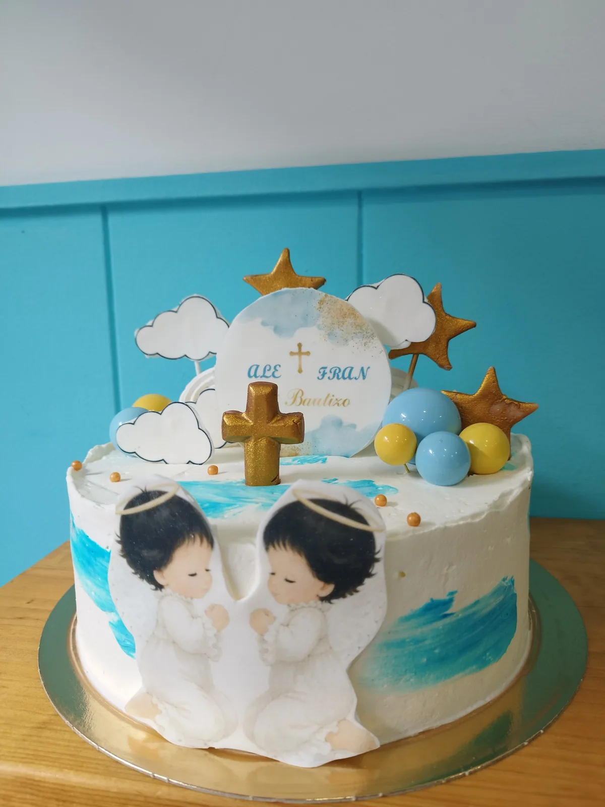 Tarta de bautizo con nubes, estrellas doradas y dos bebés modelados a mano
