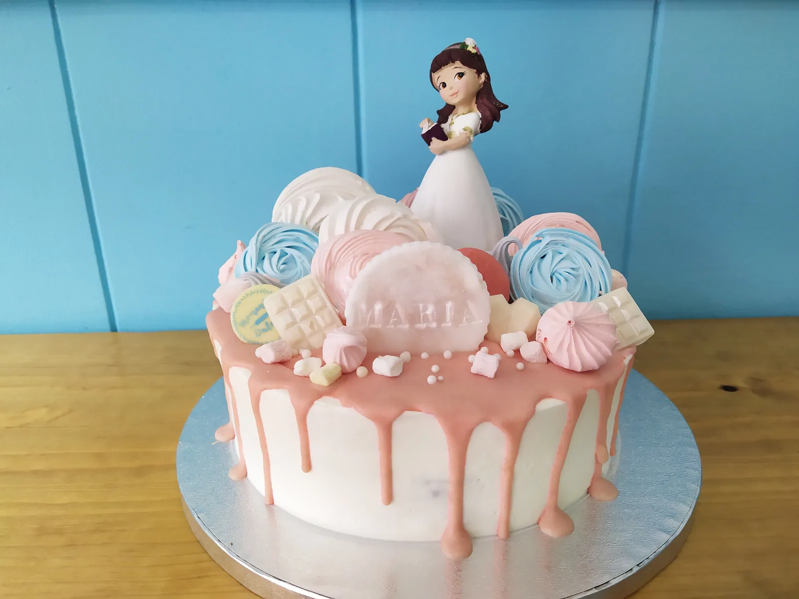 Tarta de comunión decorada con globos de fondant en tonos pastel y figura de niña