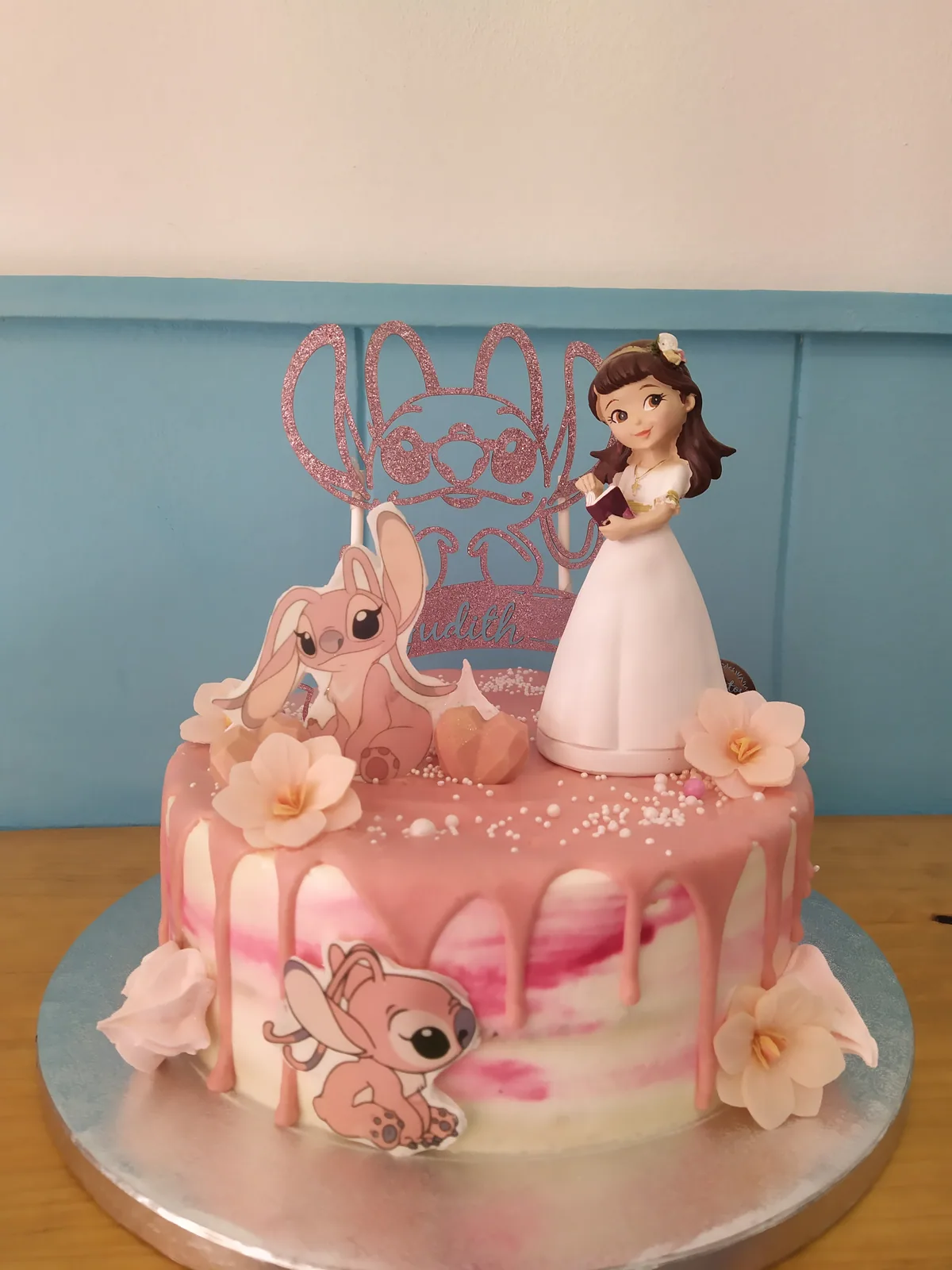 Tarta de comunión rosa con figura de niña, conejitos y flores de buttercream
