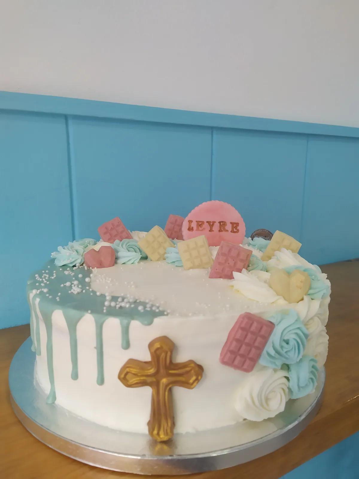 Tarta de comunión con cruz de fondant, drip de chocolate blanco y macarons