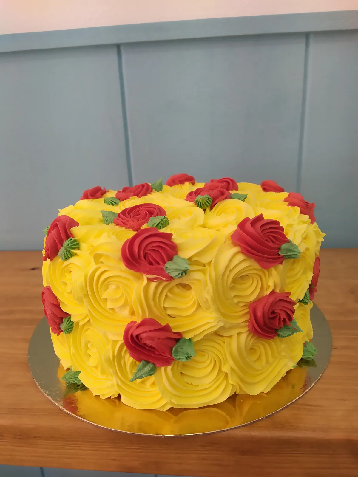 Tarta con rosas de buttercream amarillas y hojas verdes