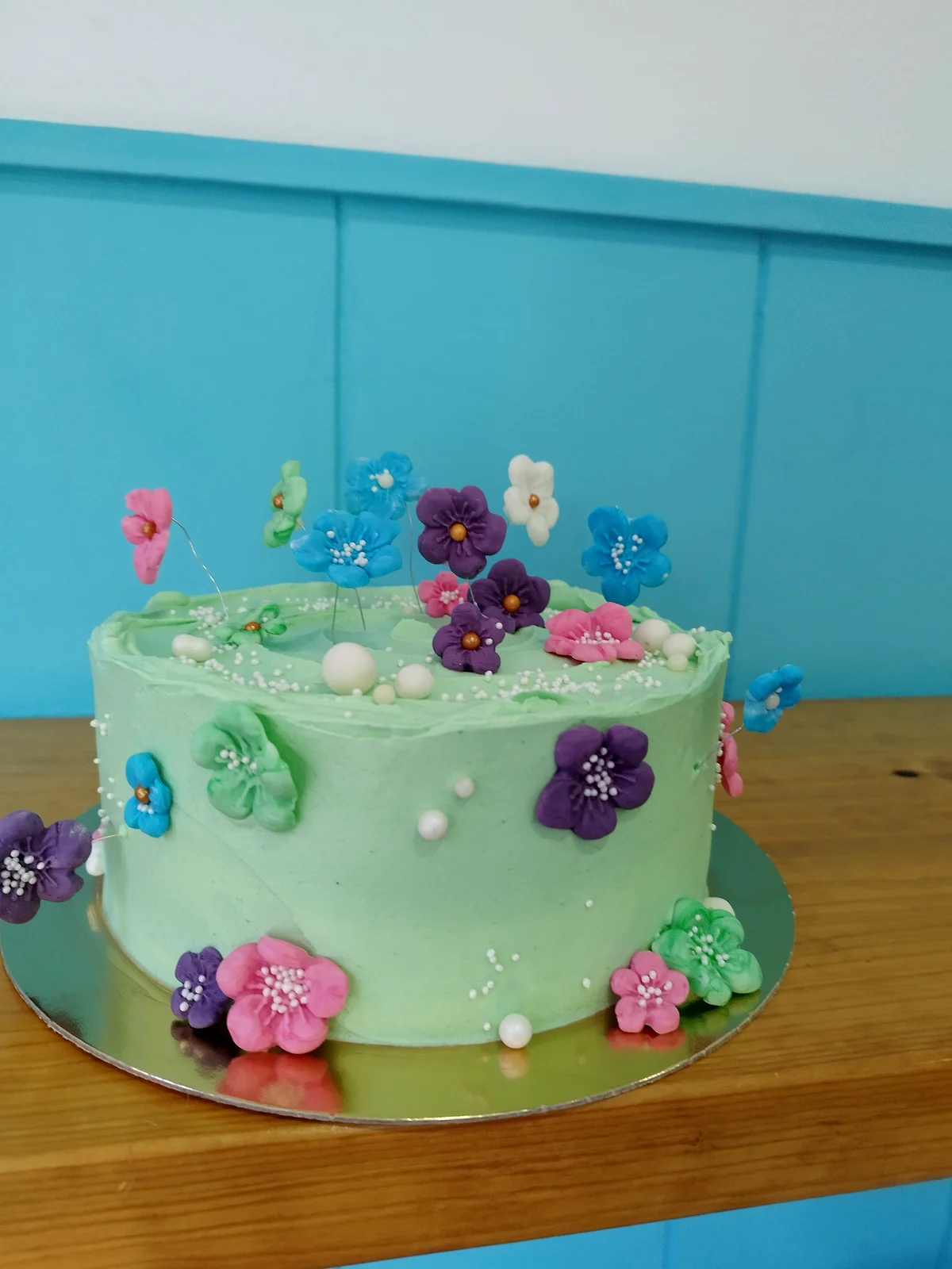 Tarta en verde agua con flores de azúcar de colores y perlas