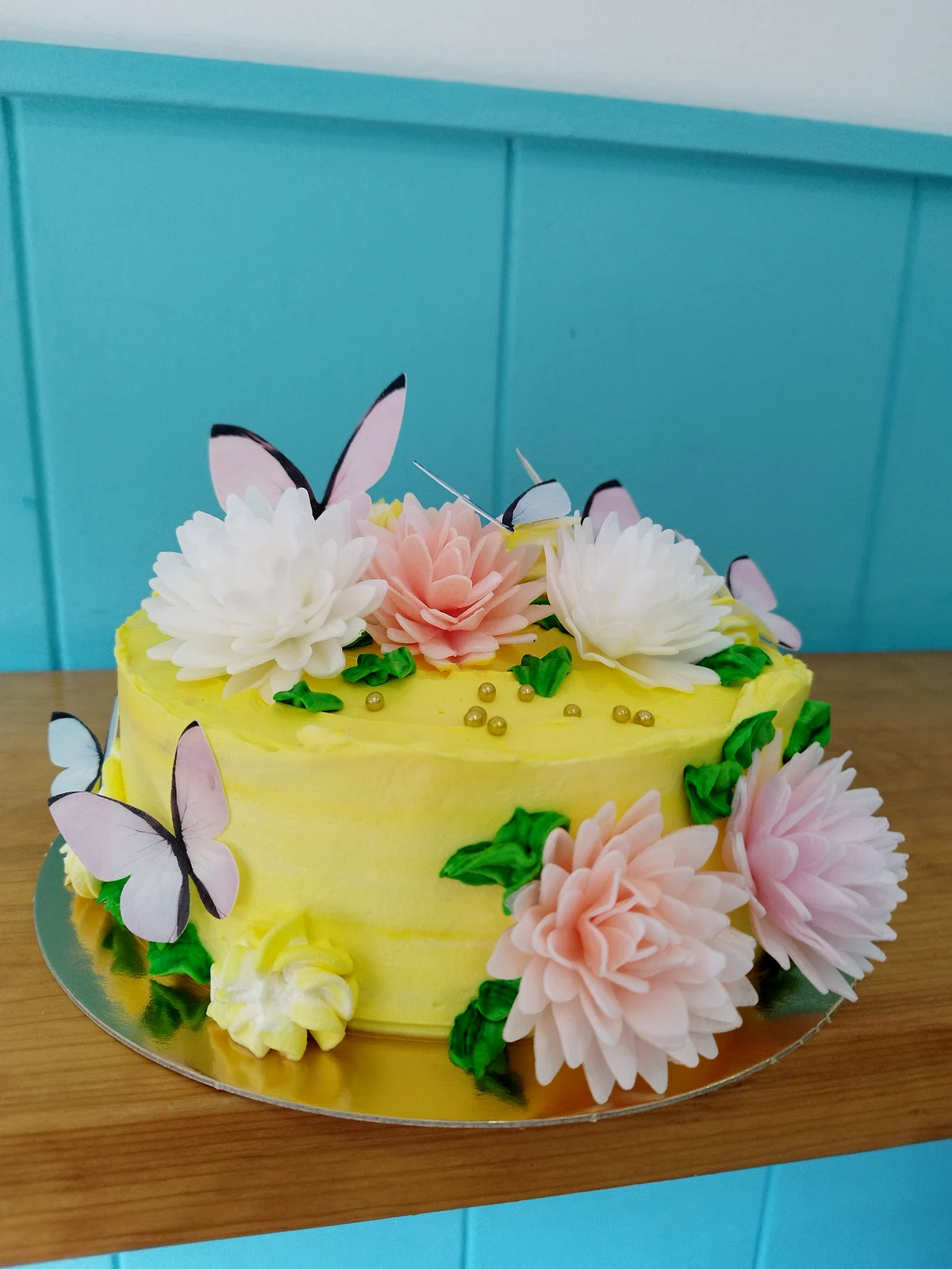 Tarta en amarillo con flores de fondant rosas y blancas y mariposas