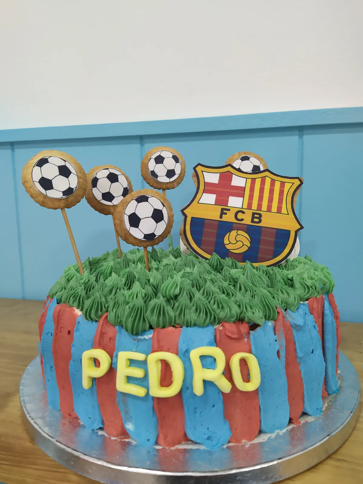 Tarta del FC Barcelona con césped de buttercream, balones y el escudo