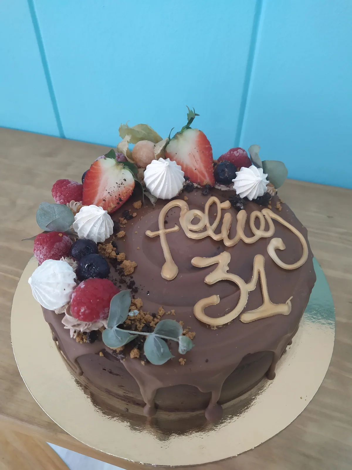 Tarta con frutos rojos y merengues en un lado y mensaje escrito a mano