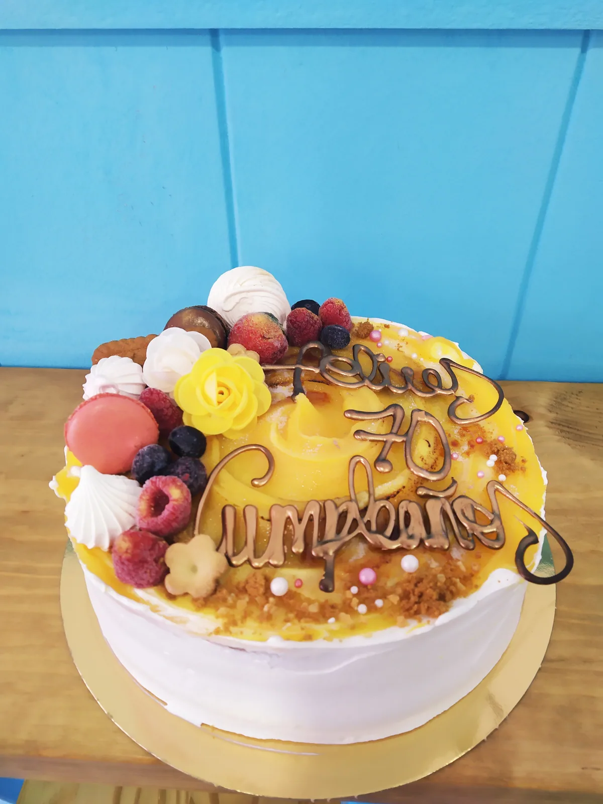Tarta con drip amarillo, frutos rojos y merengues concentrados en un lado