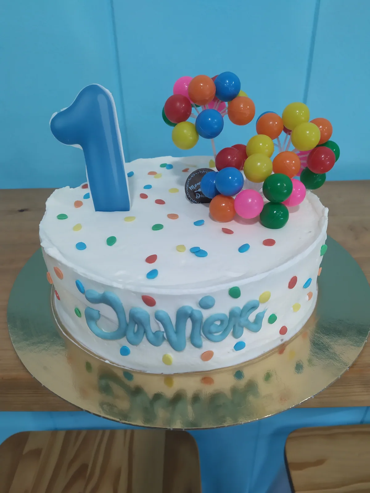 Tarta de primer añito celeste con globos de colores y el número uno