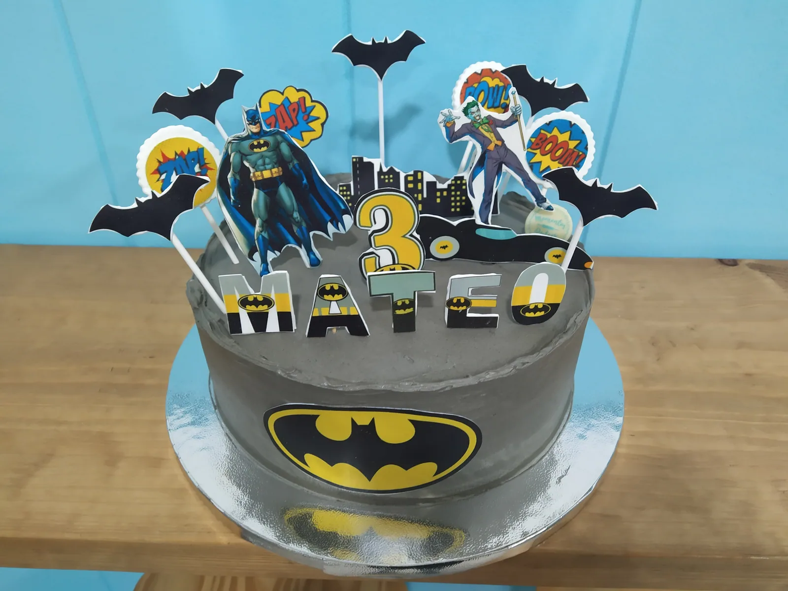 Tarta de Batman en gris y amarillo con el murciélago y la ciudad de fondo